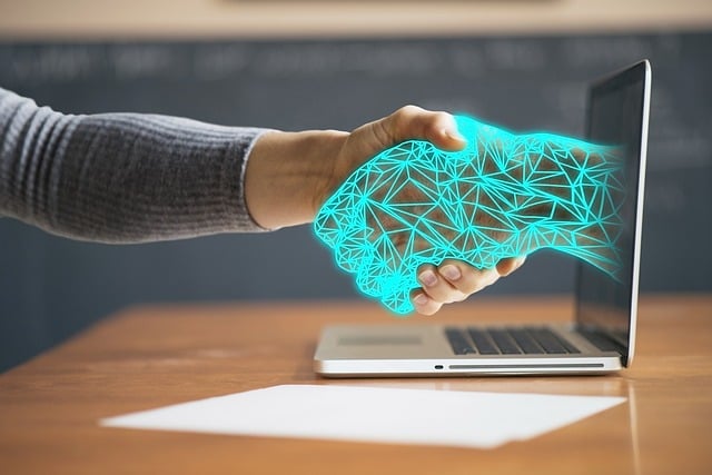 Physische und digitale Hand reichen sich durch den Laptop due Hände 